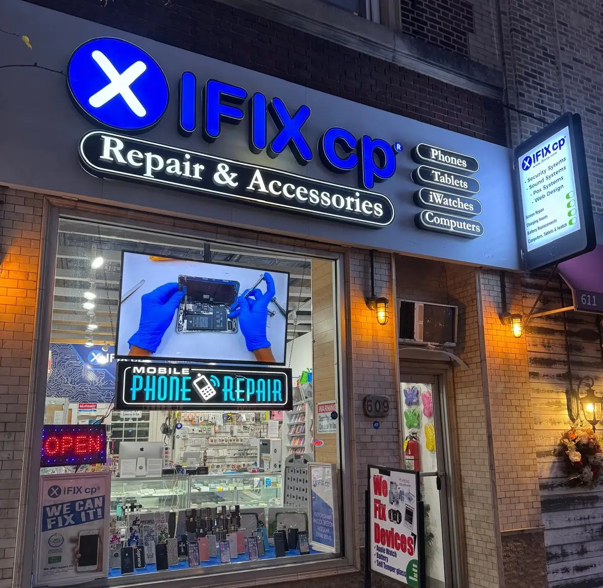 The iFixCp storefront at night, illuminated 'IFIX cp Repair & Accessories' sign
